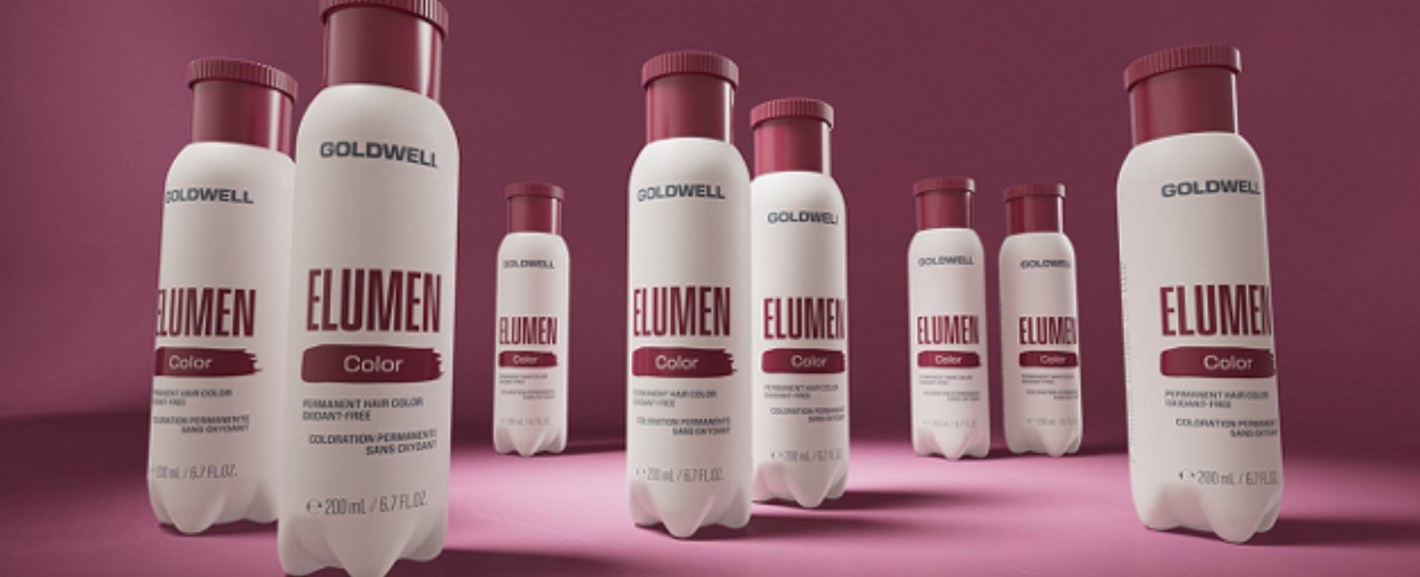 Goldwell Elumen Color -hiusvärituotteita, useita pulloja ja pulloja vaaleanpunaisella taustalla.